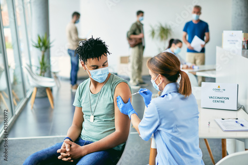 Young African American man getting vaccinated against coronavirus at vaccination center.