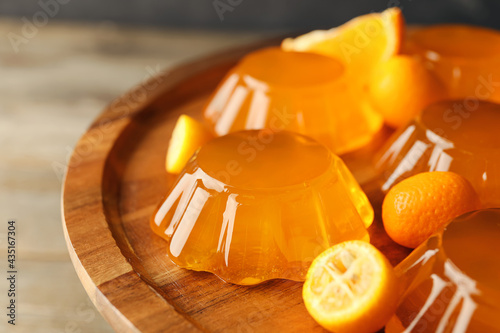 Plate with tasty orange jelly on wooden background, closeup