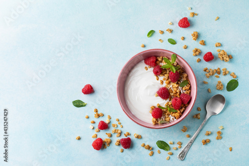 Bowl with greek yogurt, raspberries and granola. Top view flat lay. Healthy nutrition breakfast.