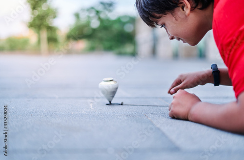 Closeup of a caucasian boy playing with a spinning top in the park