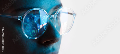 Close up view of blue eye in glasses with futuristic holographic interface to display data. Portrait of beautiful young woman, half of face. Augmented reality, future technology, internet concept.