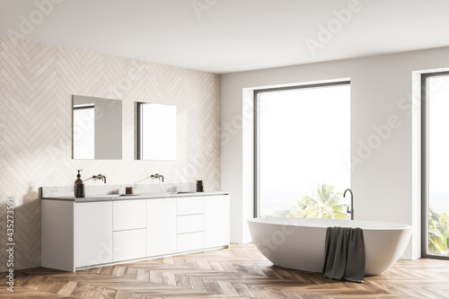 Spacious modern bathroom design interior in wood tones with parquet floor, freestanding tub, double sink vanity. Panoramic window.