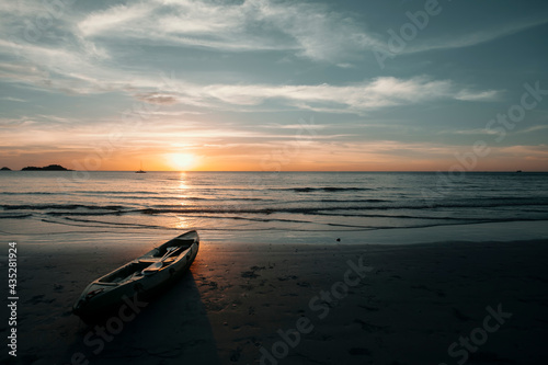 A kayak lies on the beach during a beautiful sunset.