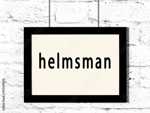 Black frame hanging on white brick wall with inscription helmsman