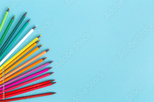 Colored pencils on a blue background. A simple multicolored template with copy space for a school or preschool theme. Drawing, sketching. Stationery. The concept of versatility creative thinking.