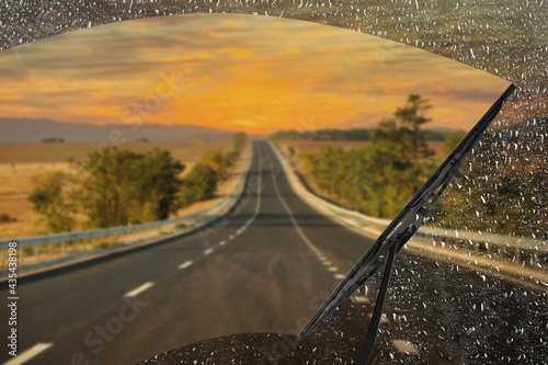 Car windshield wiper cleaning water drops from glass while driving