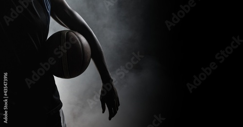 Composition of athletic male basketball player over smoke on black background