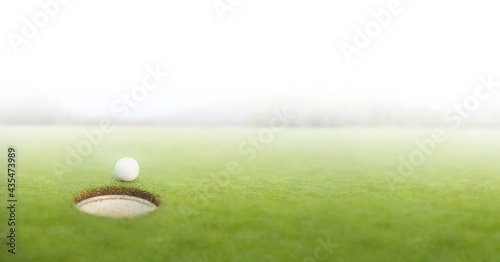 Composition of golf ball on golf course over white blur