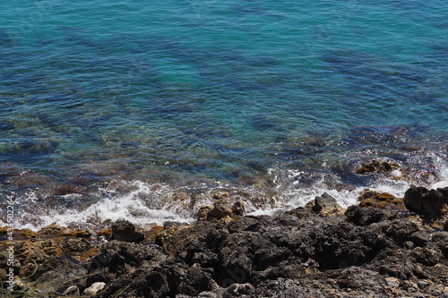 Brzeg morza, ciemne kamienie i przezroczysta woda, Kreta, Grecja