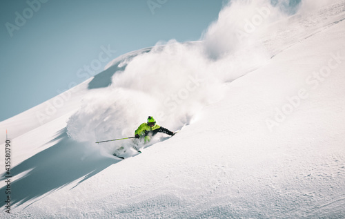 Skier rides in the mountain against the blue sky on fresh snow