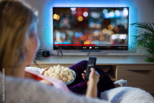 Woman relaxing at home in evening and watching TV