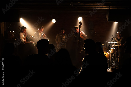 WIDE People dancing during concert of a modern jazz band playing on a stage of a small crowded venue