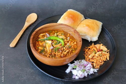 Spicy Misal Pav or usal Pav is a traditional snack or Chaat food from Maharashtra, India. Served with chopped onion, lemon wedges and farsan. Selective focus with copy space