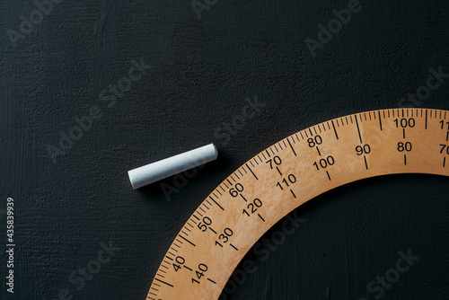 piece of chalk and protractor on a chalkboard