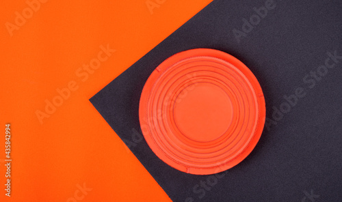 Orange clay target on black and orange geometric background. Skeet shooting