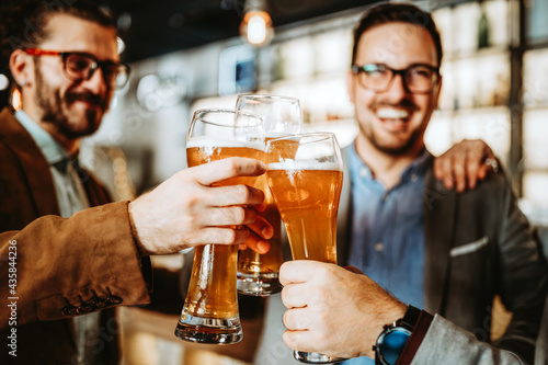 Business people drink beer after work in pub. Businessmen enjoy a beer.