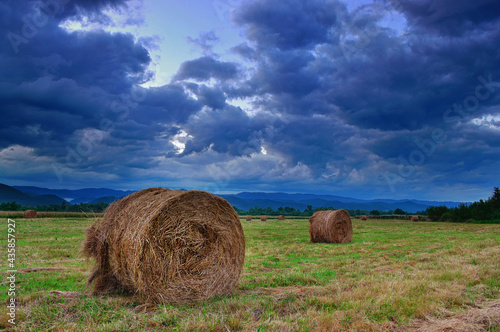 Hay bales in a storm sky.