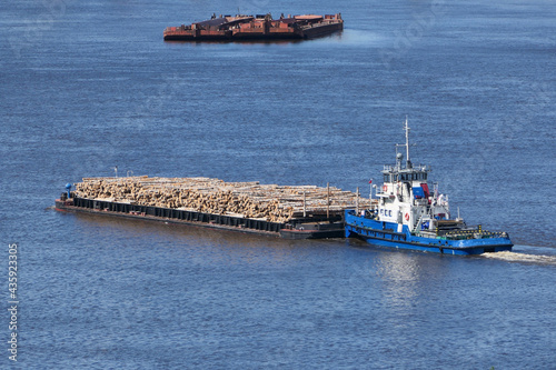 The barge transports cargo, timber logs along the river in summer. High quality photo