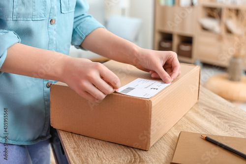 Young woman preparing parcel for client at home, closeup