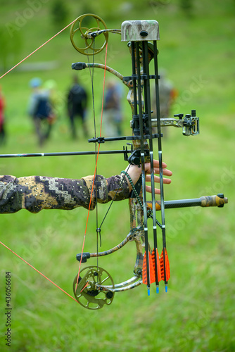 professional archer shooting with modern longbow at meadow