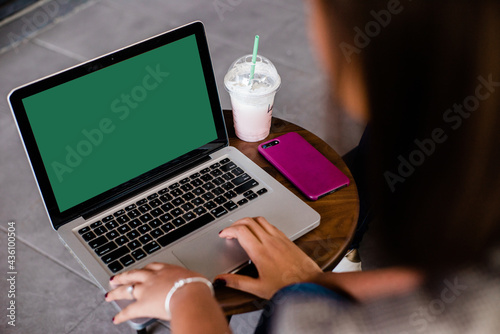Persona escribiendo en la computadora sentada con una bebida en un vaso