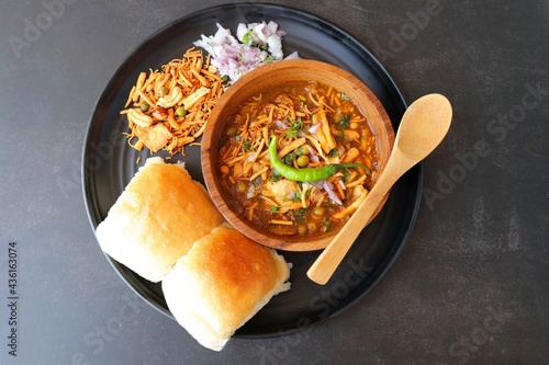 Spicy Misal Pav or usal Pav is a traditional snack or Chaat food from Maharashtra, India. Served with chopped onion, lemon wedges and farsan. Selective focus with copy space