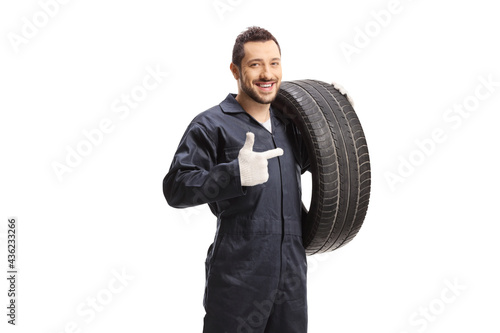 Auto mechanic holding a of car tire and pointing