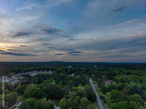 a breathtaking aerial panoramic shot of a sunset over Powder Springs Georgia with miles of vast green trees and homes with powerful clouds