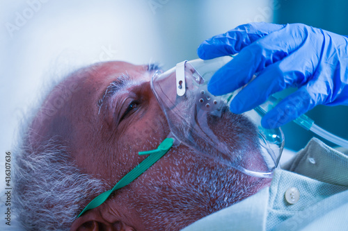 Close up shot, Doctor helping by adjusting ventilation oxygen mask to covid infected difficulty in breathing or breathlessness to patient at hospital - Concept of dyspnea due to coronavirus infection