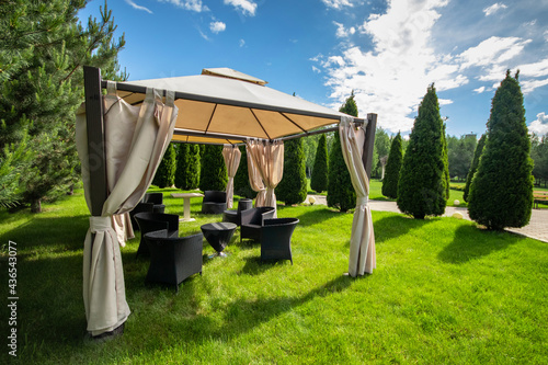 White canvas gazebo with plastic garden furniture in a summer green lawn