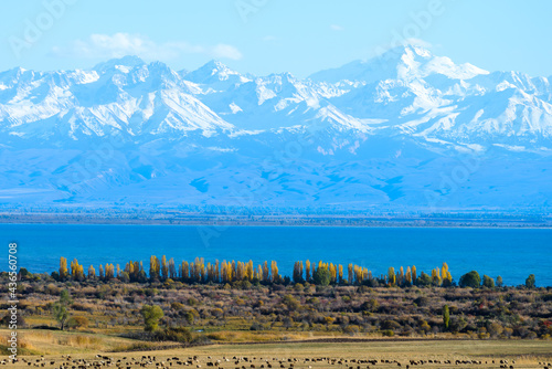 Issyk Kul Lake in Kyrgyzstan surronded by Northern Tian Shan mountains in fall season. Kyrgyz alpine lake in National Park with snow capped mountain.