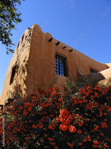 an historic abode building orange flowers on a sunny day in the santa fe plaza, santa fe, new mexico