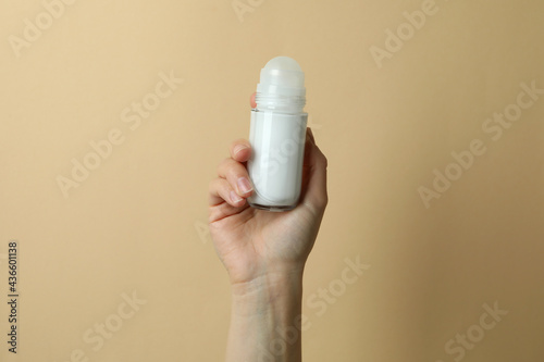 Female hand holds blank deodorant on beige background