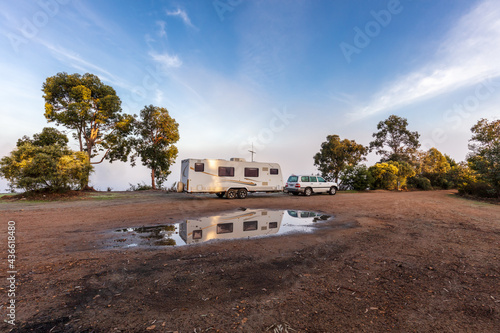 Landscape view of a large modern caravan and fourwheel drive camped near trees and a lake on a foggy morning near Collie in Western Australia