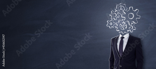 Headless businessman with abstract gear sketch standing on chalkboard background with copy space. Engineering and brainstorm concept.