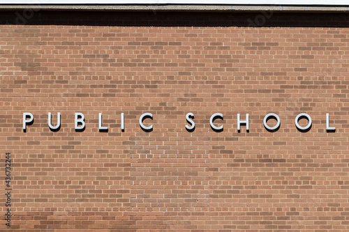 PUBLIC SCHOOL in stainless steel text against a brick background.