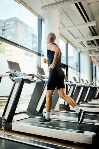 Below view of mature athlete running on treadmill in a gym.