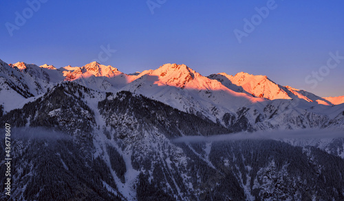 Soft morning sunlight on mountain ridges; rocky mountains covered with snow at sunrise