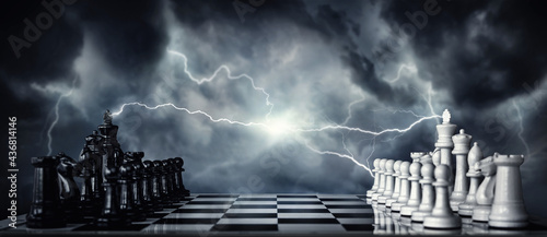 Chess pieces on a chessboard against the backdrop of a stormy sky and flashing lightning. The game of chess as a symbol of strategy, leadership, tactics and business victories. 