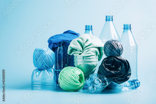 Empty plastic bottle and various fabrics made of recycled polyester fiber synthetic fabric on a blue background