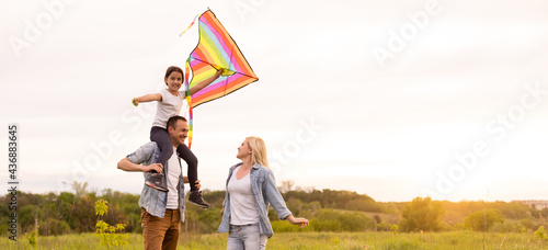 Happy family father, mother and child daughter launch a kite on nature at sunset