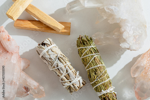 White sage, cedar, crystals, and Palo Santo sticks tied by a bundle on a light background. A set of incense for fumigation. Top view. Organic incense from Latin America. Color photo close-up.