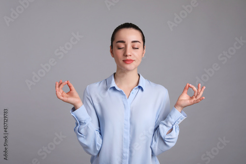 Young woman meditating on light grey background. Personality concept