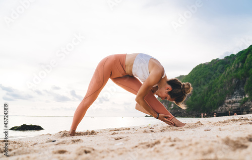 Slim female athlete stretching body