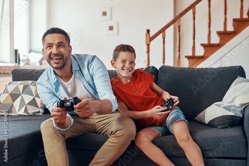 Happy young father and son playing video games while spending time at home