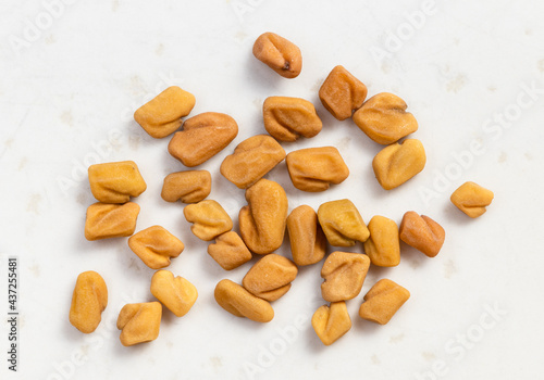 several whole fenugreek seeds close up on gray