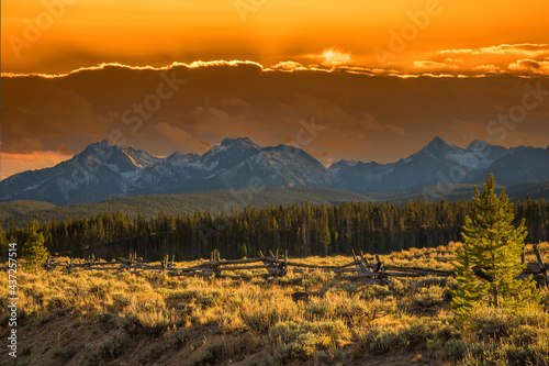 A split rail fence and a sage brush meadow with the Sawtooth mountains in the background, in the fall season near Stanley, Idaho.