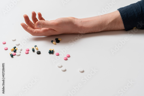 human outstretched hand laying with dose of pharmacy and medicine pills, overdose concept