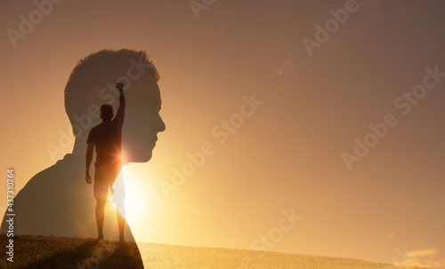 Silhouette of strong young man feeling determined, empowered and motivated putting fist up to the sky. People power and inner strength concept. 