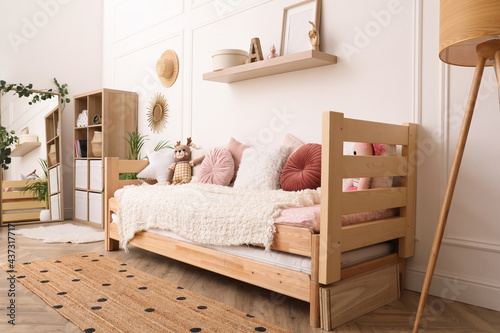 Cute child's room interior with comfortable bed and toys